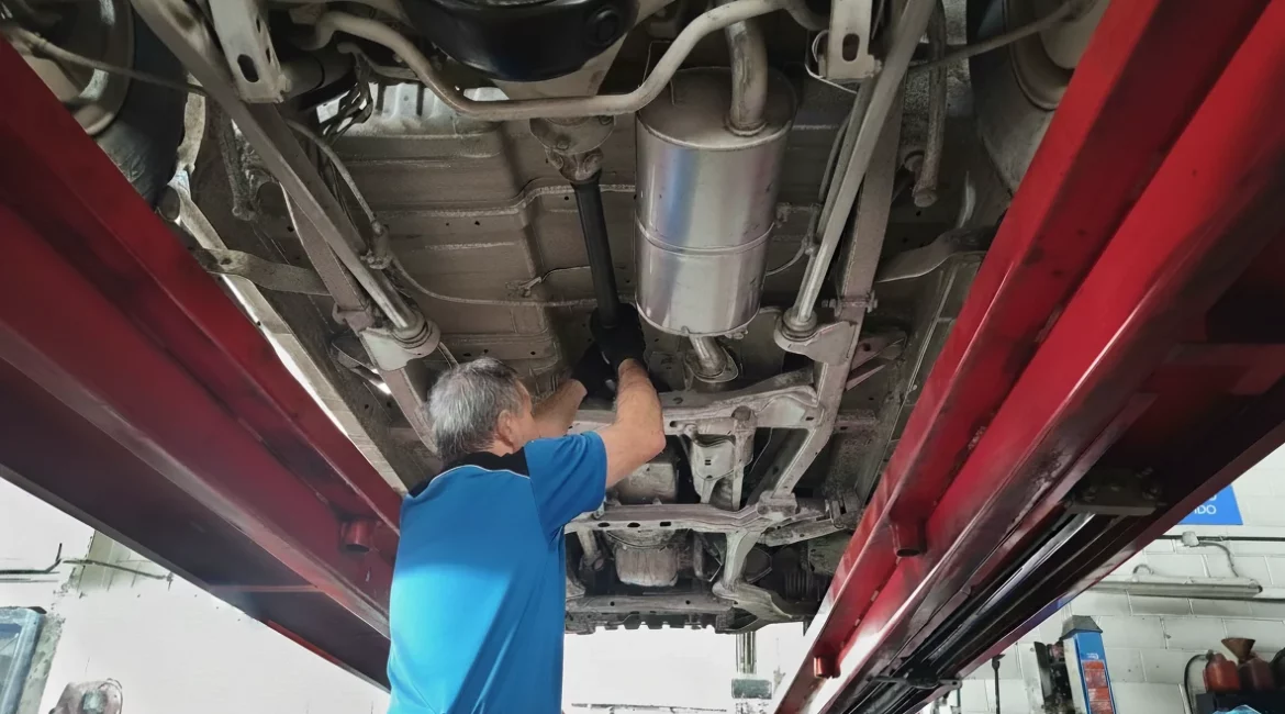 Mechanic working on the driveshaft, lifted on a four-post hydraulic lift