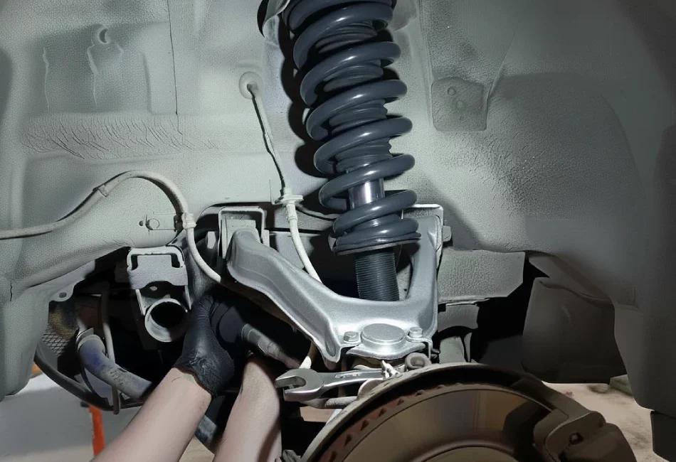 Mecánico de coches en un taller reparando la suspensión trasera (amortiguador y muelle) de un vehículo